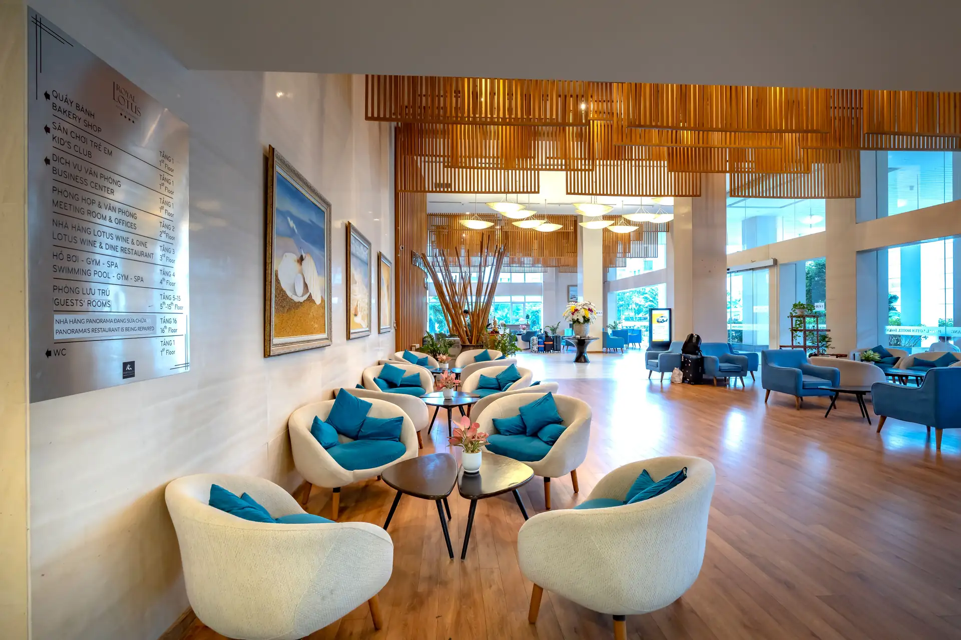 Saguão de hotel claro com poltronas e piso de madeira