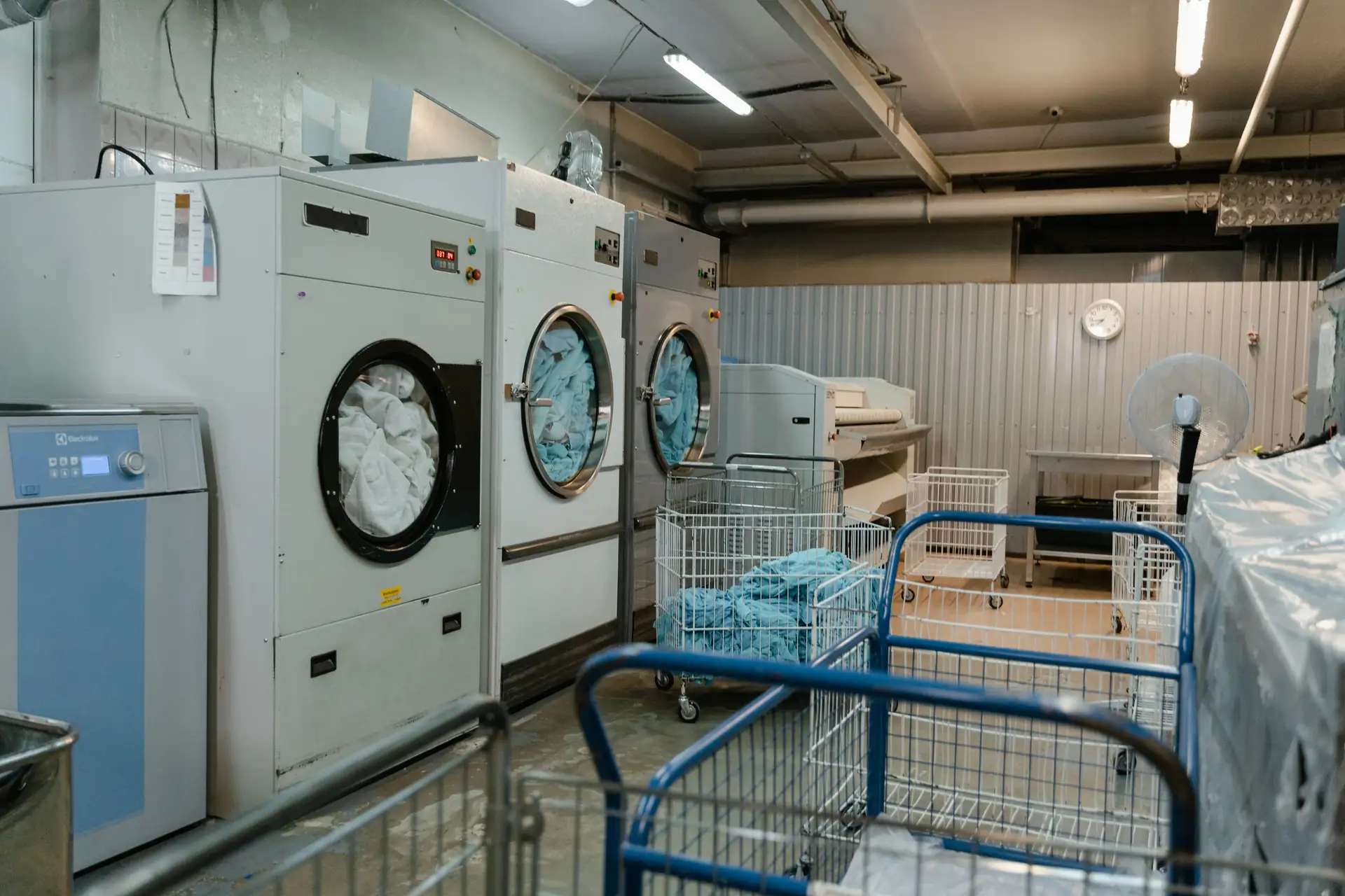 Lavanderia industrial com lavadoras e carrinhos de enxoval