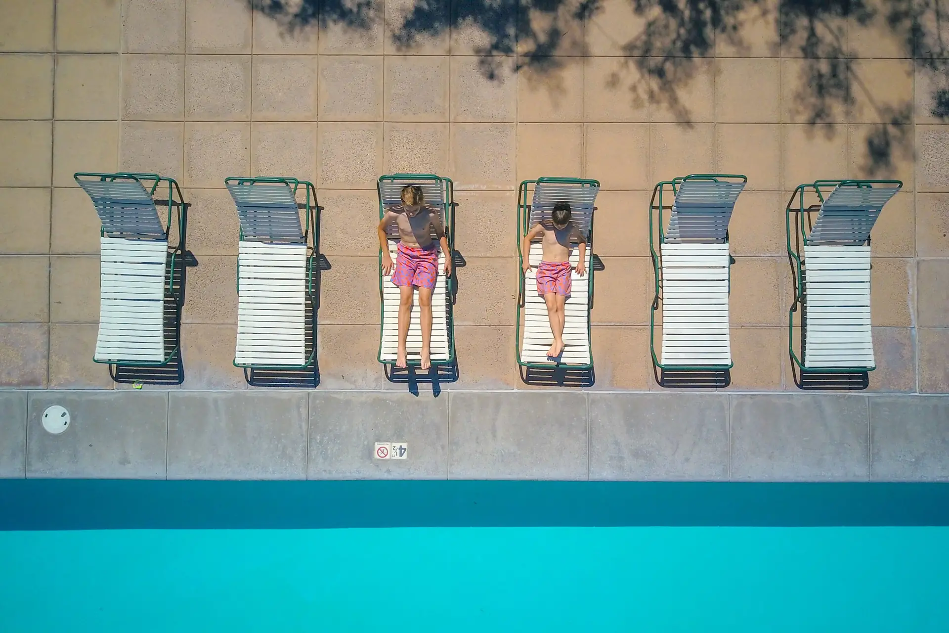 Vista de cima de espreguiçadeiras à beira de uma piscina de clube