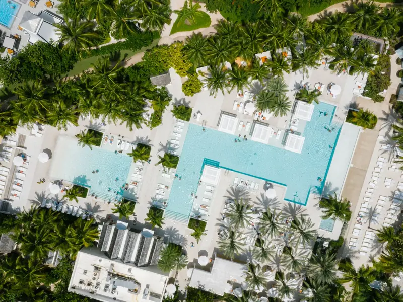 Vista aérea de um clube com piscinas, jardins e espreguiçadeiras