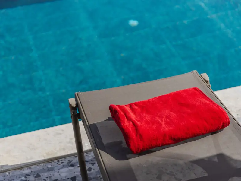 Toalha vermelha dobrada sobre uma espreguiçadeira à beira da piscina