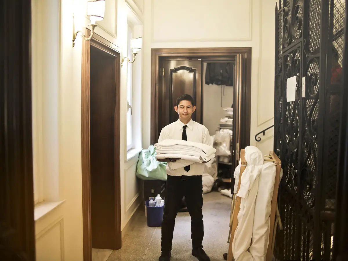 Funcionário do hotel carregando roupa de cama limpa na rouparia